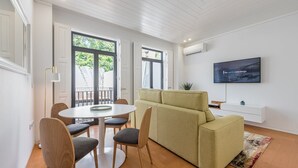 Un soggiorno moderno con divano, tavolo da pranzo e sedie, televisore a schermo piatto e un balcone con vista.