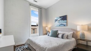 Un dormitorio moderno con una cama grande, dos mesitas de noche, un escritorio y una ventana con cortinas.