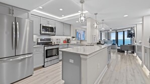 Een moderne keuken met roestvrijstalen apparatuur, een centraal eiland en hanglampen.
