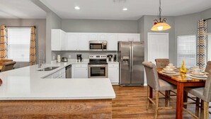 A modern kitchen with white cabinets, stainless steel appliances, and a central island.