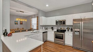 A modern kitchen with white cabinetry, stainless steel appliances, and a large island.