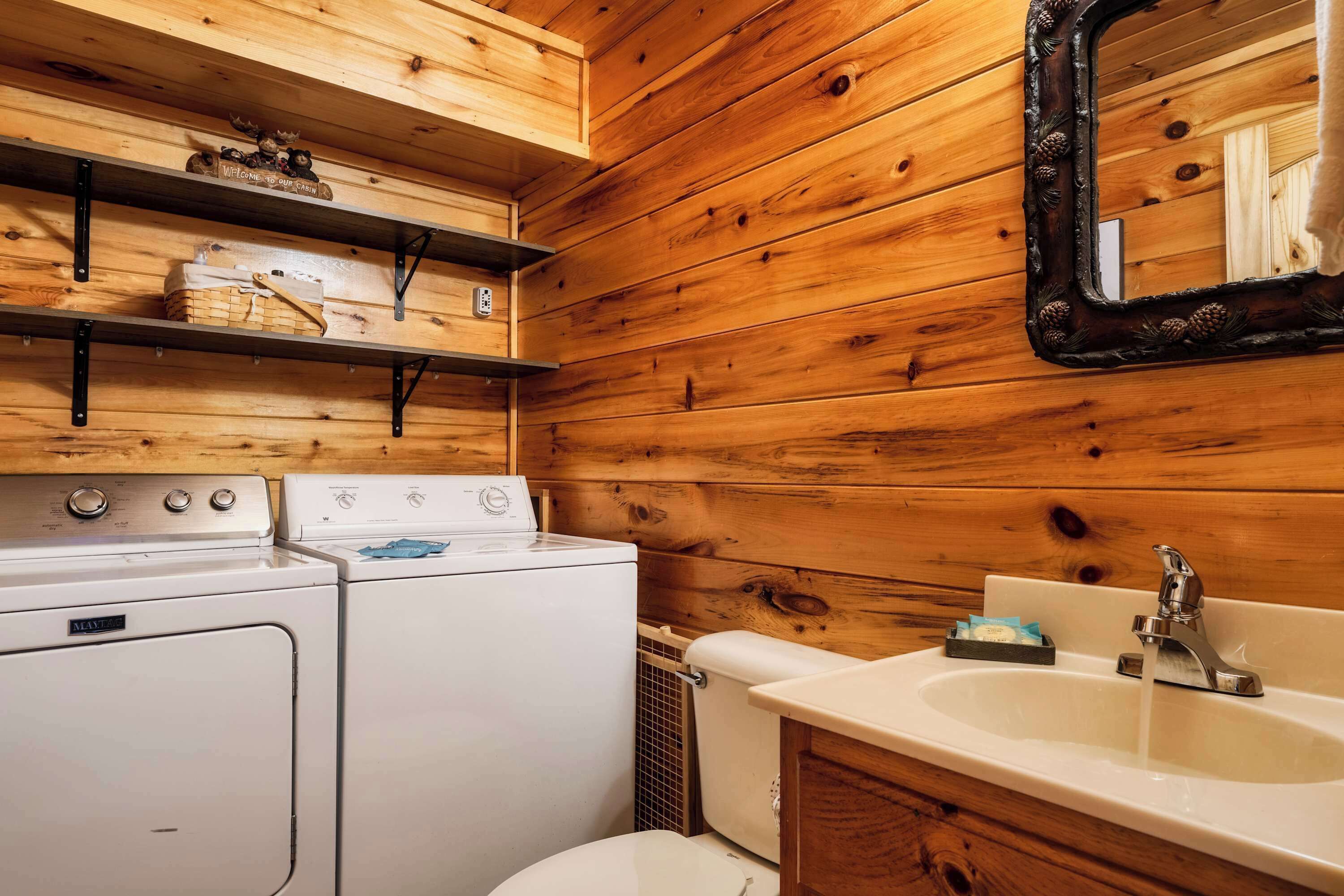 Ein Badezimmer einer Holzhütte mit Waschmaschine, Trockner und Waschbecken.