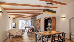 A spacious living area with a wooden dining table, chairs, and a sofa. A staircase leads to another level. - Charming house -A STALLA- Between Sea and Mountain (Muro Hute Corse)
