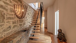 A staircase with a stone wall on one side and a wooden floor, leading to a room with a table and a statue. - Charming house -A STALLA- Between Sea and Mountain (Muro Hute Corse)