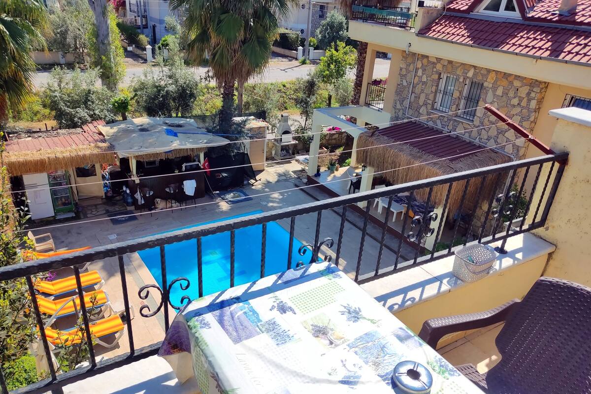 Un balcon avec piscine, un espace salon extérieur et un coin barbecue.