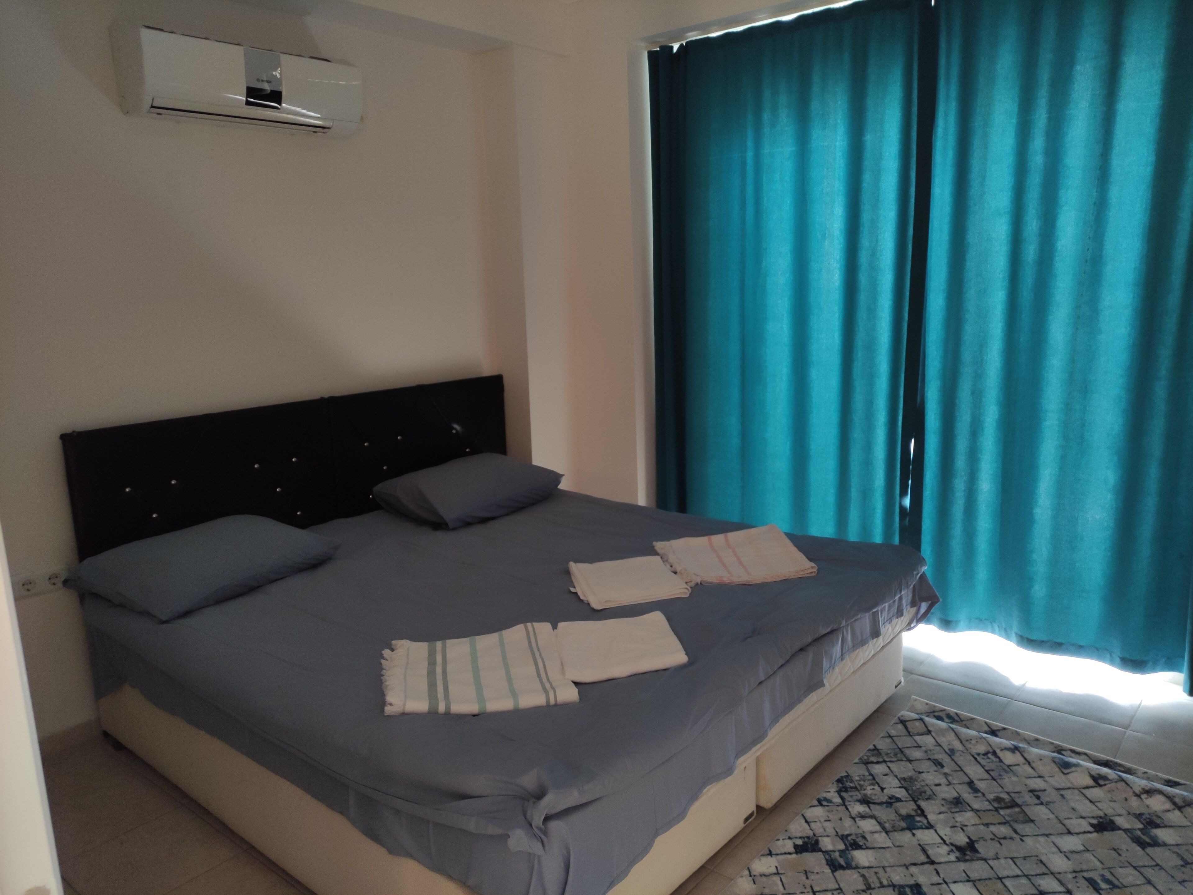 Un dormitorio con cama, almohadas, una colcha y una alfombra.