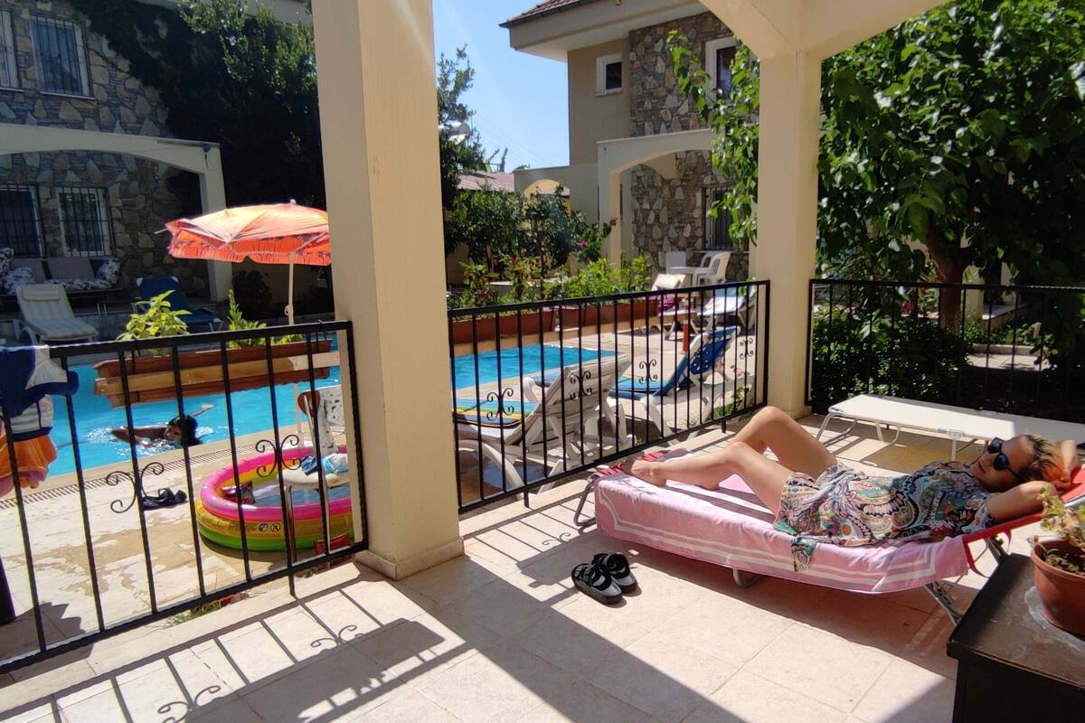 Un balcon avec une piscine, des chaises longues et un pot de fleurs.