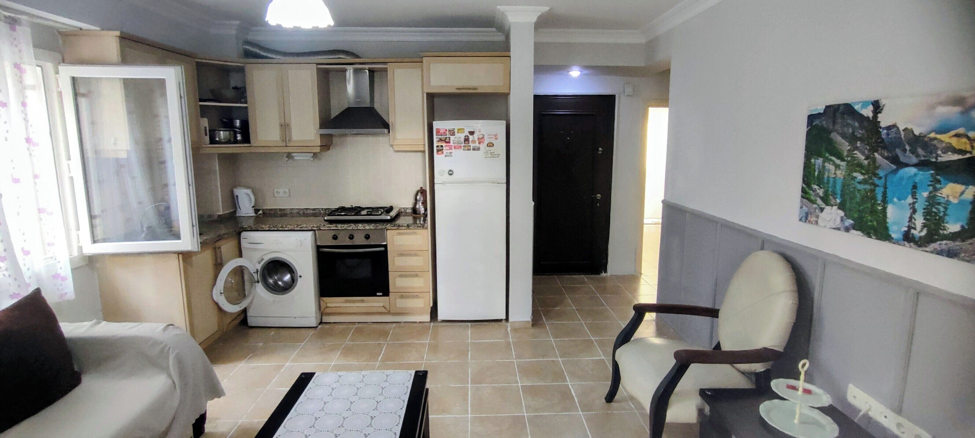 A compact kitchen with a stove, oven, washing machine, and a refrigerator.