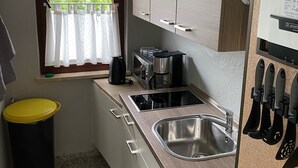 Une cuisine de taille réduite, équipée d’un évier, d’une cuisinière et de placards.