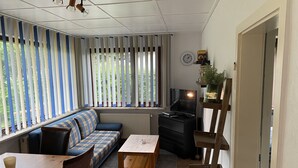 Un salon confortable avec un canapé, une table basse, un téléviseur et une bibliothèque.