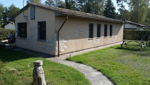 Une maison de plain-pied avec une façade en pierre, un toit en tuiles et un petit porche.