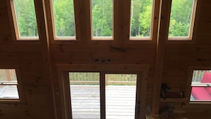 Eine Hütte mit mehreren Dachfenstern, einer Terrasse und einem Willkommensschild.
