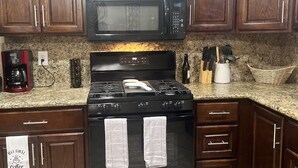 A kitchen with dark wooden cabinets, a black microwave, a stove with two towels, and a coffee maker. - Nice 3 bedroom's house owner occ and 2 bathroom with fast WI-Fi,  Full Kitchen (Las Vegas)