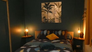Een slaapkamer met een bed, twee nachtkastjes, een kunstwerk aan de muur en een deur.