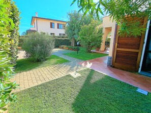 A well-maintained garden with a paved pathway leading to a building with a tiled roof.