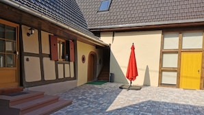 A building with a tiled roof, a wooden door, and a red umbrella.