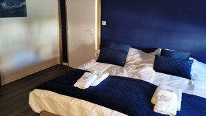 A bedroom with a bed, pillows, and a door.