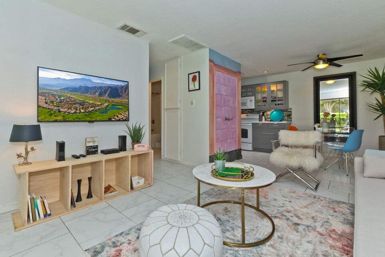 Een moderne woonkamer met een flatscreen televisie, een houten console, een ronde salontafel en een zachte fauteuil.