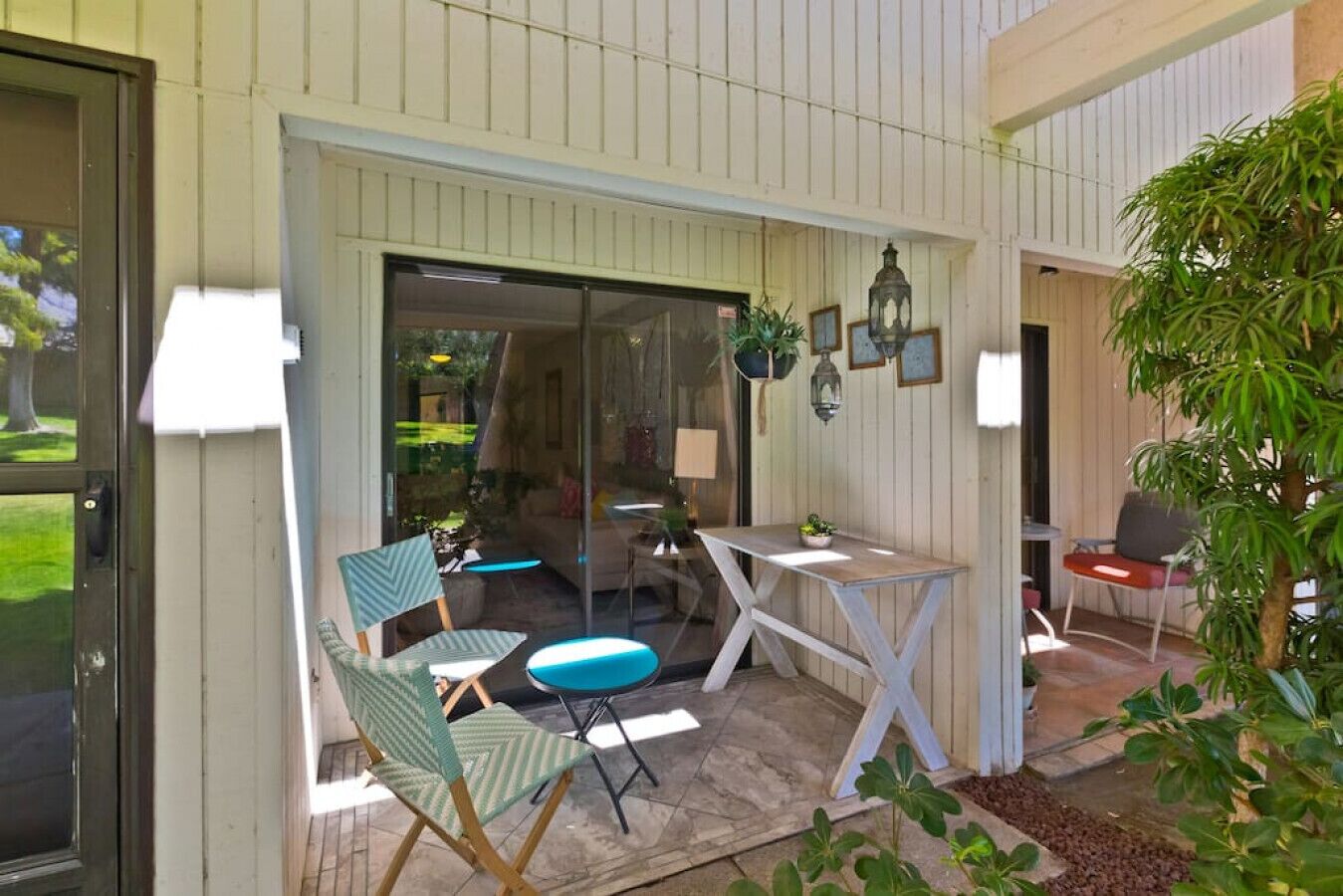 A covered patio area with a table and chairs, a small seating area, and a view into the house.