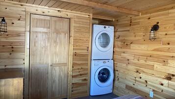 Een kleine kamer met houten wanden, een dubbele deur en een gestapelde wasmachine en droger.