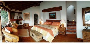 Een gezellige slaapkamer met een houten bed, een bank, een dressoir en een trap naar een hoger gelegen verdieping.
