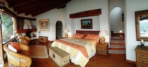 Un dormitorio acogedor con una cama de madera, un sofá, un aparador y una escalera que conduce a un nivel superior.