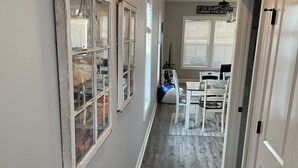 Een hal met een houten vloer, een vloerkleed en een eethoek met een tafel en stoelen.