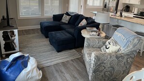Een moderne woonkamer met een hoekbank, een fauteuil met een patroon en een bijzettafeltje.