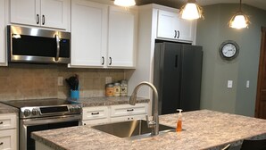 A modern kitchen with white cabinets, stainless steel appliances, a granite countertop, and pendant lighting. - Forest Estate Guest Quarters-Seclusion- Just Minutes from Town (Woodland Park)