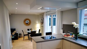 A modern kitchen with a central island, dining area with a round table, and a living space with a sofa and a coffee table.