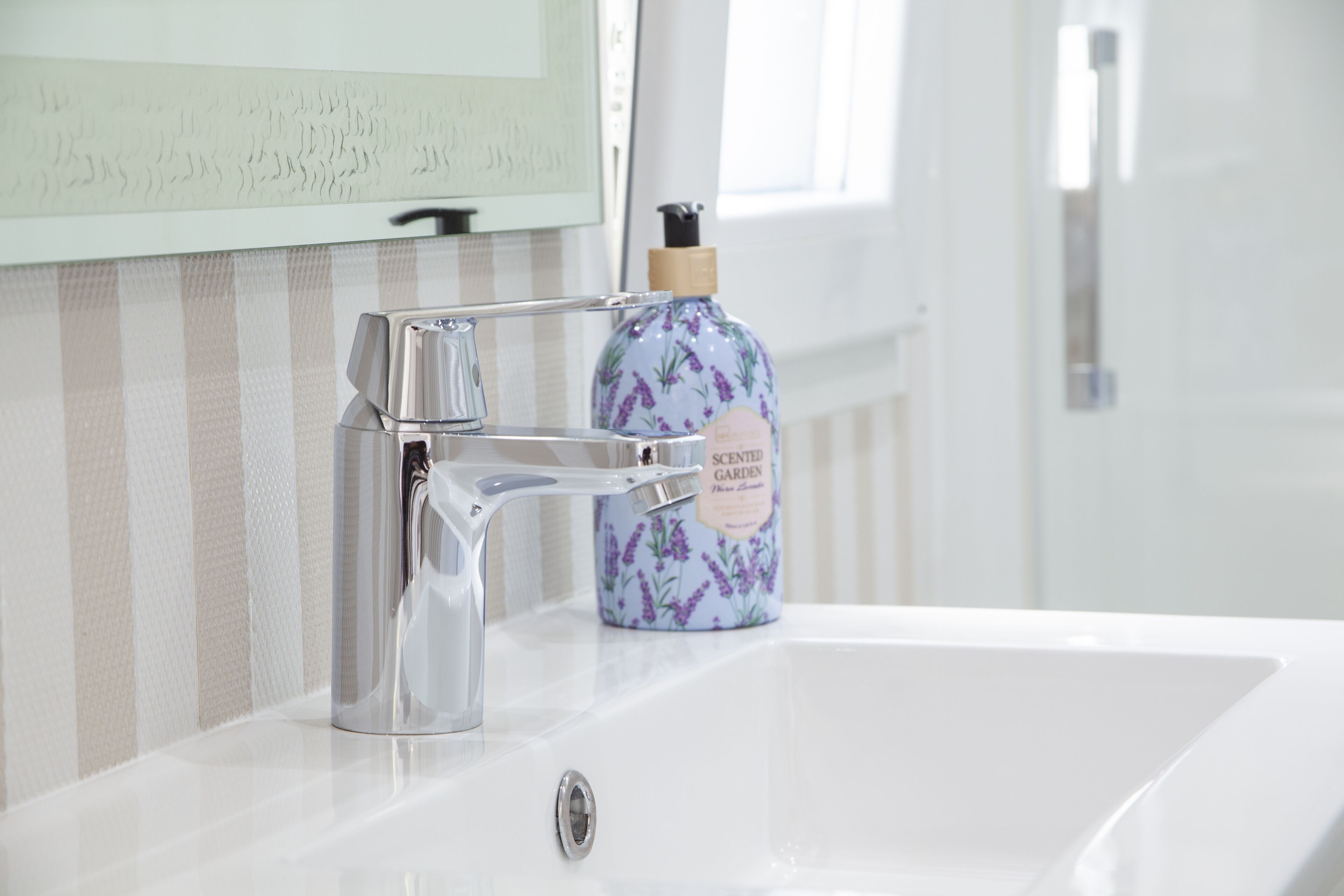 Un lavabo in bagno con un moderno rubinetto e una saponetta profumata al giardino.