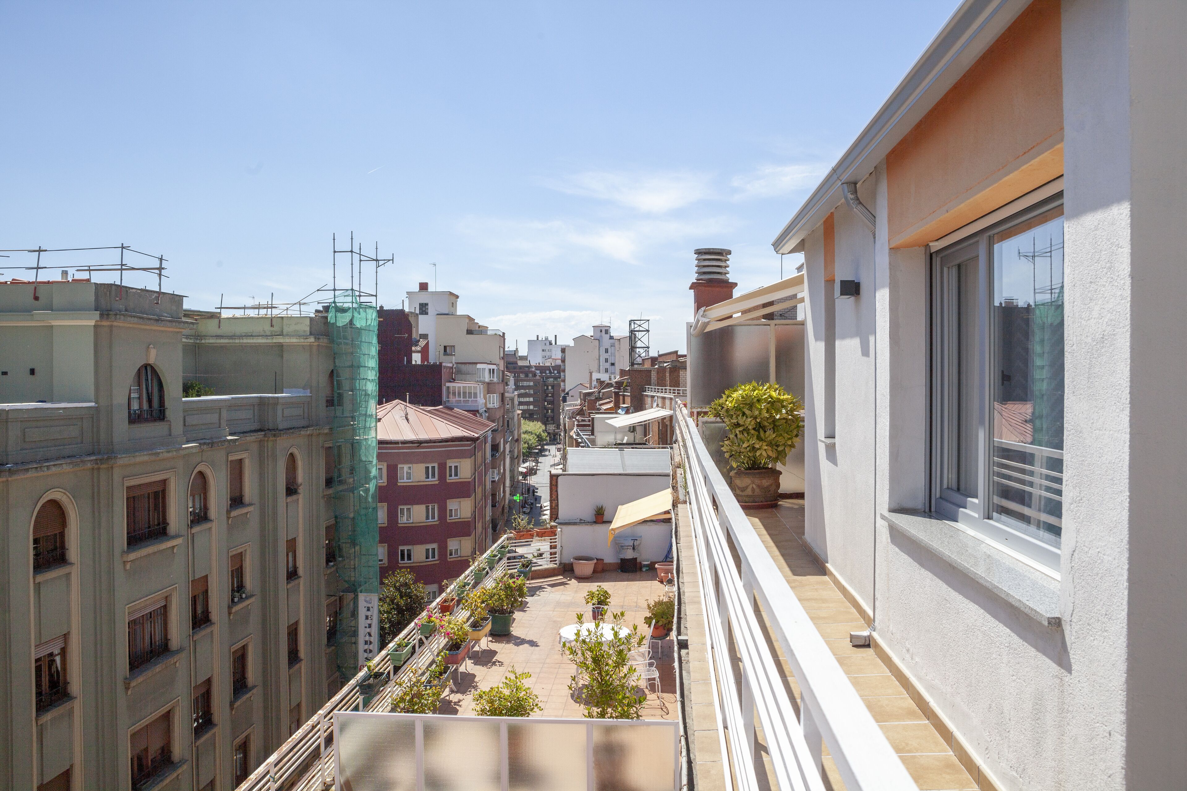 Un balcón con vista a un paisaje urbano, que incluye edificios y cielo despejado.