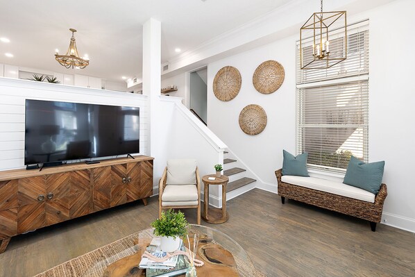 Un salon moderne doté d’un téléviseur à écran plat, d’un meuble en bois et d’un escalier menant à un autre niveau.