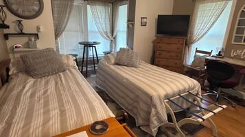 Une chambre avec deux lits, une télévision, une horloge et une pancarte indiquant : « Bienvenue. Emplacement idéal. »