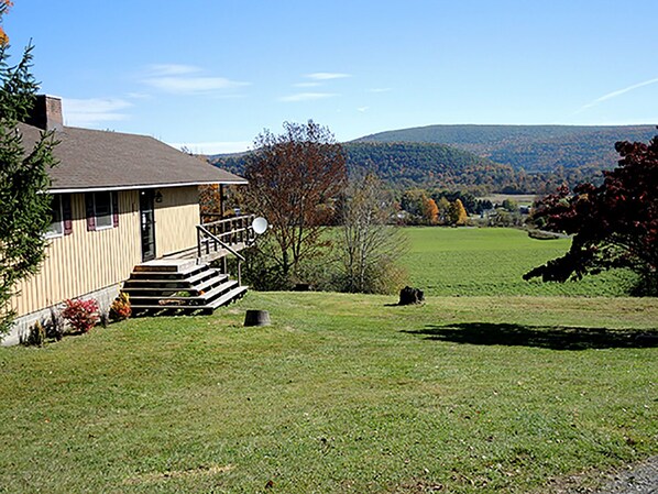 Une maison à deux étages avec un porche à l’avant et une antenne parabolique.