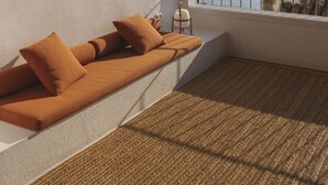 A modern room with a built-in sofa, a view of a harbor, and a woven rug.