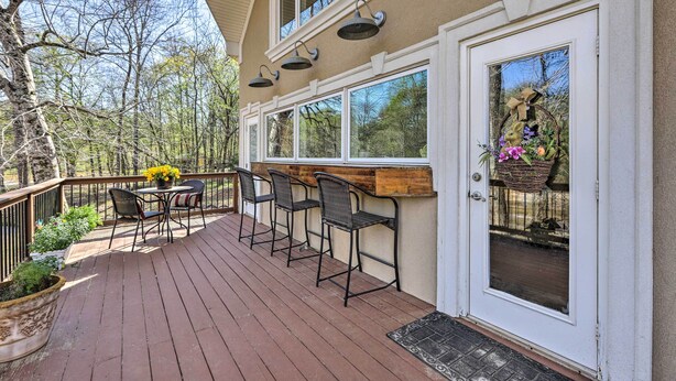 Una terraza con asientos exteriores, una barra de madera y una puerta con un cesto decorativo.