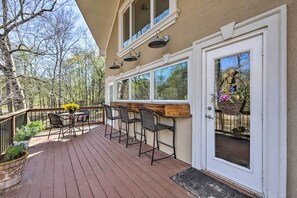 Una terraza con asientos exteriores, una barra de madera y una puerta con un cesto decorativo.