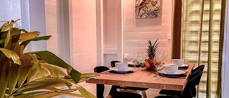 Un comedor con una mesa de madera, sillas negras y piso verde.