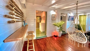 A room with a wooden bench, a hanging chair, a small stool, and a potted plant. - Jungle Cottage Orient Bay: Charming and authentic (Saint Martin)