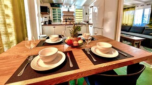 A dining area with a wooden table set for four, including bowls, plates, cutlery, and a fruit bowl. - Jungle Cottage Orient Bay: Charming and authentic (Saint Martin)