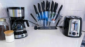 Un piano di lavoro in cucina con una macchina da caffè, un tostapane, un portatovaglioli e un barattolo.