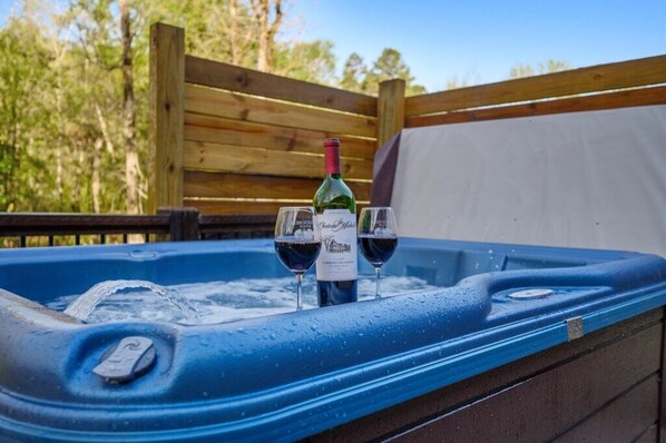 A hot tub with two wine glasses and a bottle of wine.