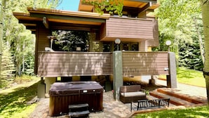 Une maison moderne dotée d’un jacuzzi, d’un espace salon extérieur et d’un chemin en pierre.