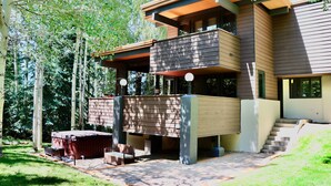 Une maison moderne à plusieurs niveaux, dotée d’une terrasse, d’un espace salon extérieur et d’un jacuzzi.