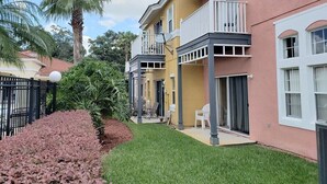 Una hilera de casas de dos pisos con balcones, una palmera y un césped bien cuidado.