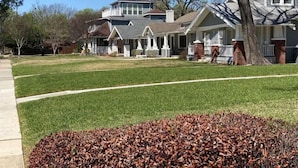 A suburban neighborhood with a well-maintained lawn, a driveway, and a row of houses with front porches and chimneys. - Cozy Studio Walk to Lower Greenville Dallas - Pet-Friendly, W/D, BBQ, Parking (Dallas)