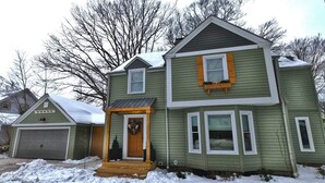 A two-story house with a front porch, a garage, and a snow-covered yard.