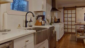 A modern kitchen with white cabinetry, stainless steel appliances, and a wooden floor.