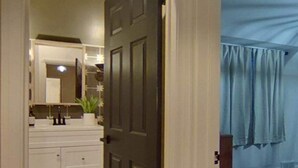 A bathroom with a white vanity, a mirror, and a dark door.
